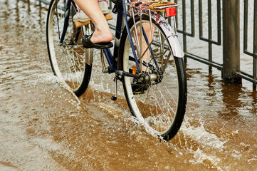 Blagoveshchensk, Russia - June 21, 2021: Father and child ride a bicycle along a flooded city...