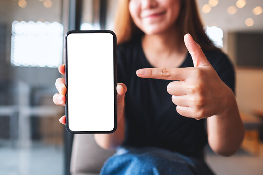 Mockup Image Of A Beautiful Woman Pointing Finger At A Mobile Phone With Blank White Screen