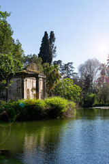 Fototapeta na wymiar Pond in the English Garden of the Royal Palace in Caserta. In the middle is a small island with an old temple with columns. Caserta, Italy
