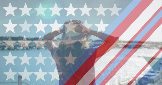 American flag design pattern and multiple stars against rear view of woman standing on a wooden pier
