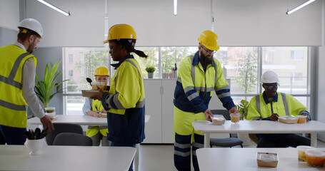 Construction company workers having takeaway lunch in modern office