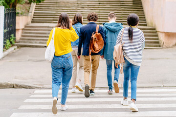 Urban teenage hipster street lifestyle.Rear view of students go to college or high school to study. Crosswalk traffic laws concept.