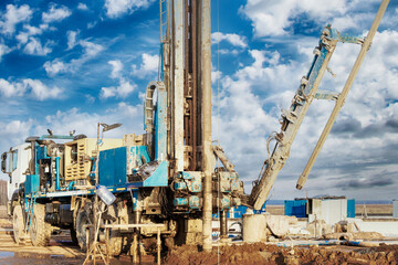 Fototapeta na wymiar Drilling rig in a field under a blue cloudy sky. Drilling deep wells. Geological exploration. Mineral exploration.