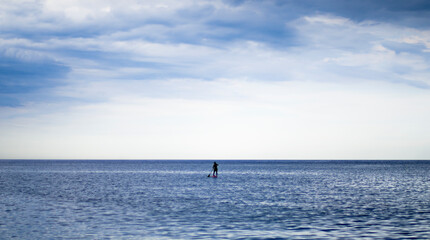 One man achieving balance while paddle surfing in calm waters of de mediterranean sea