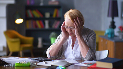 Sad frustrated senior woman having depressed calculating family budget