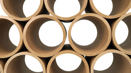 Stack of a bunch of paper tube cores, tissues, in front of white wall . Raw product material of brown paper rolls.