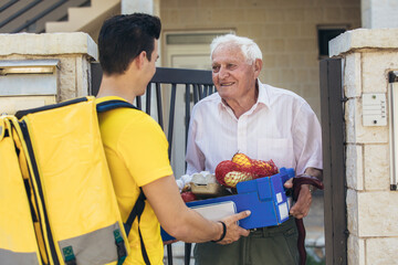 Young male volunteer delivering shopping to senior man. Donation