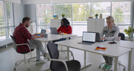 Group of diverse students or employees using laptop studying and working at open space office