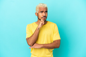Young Colombian handsome man isolated on blue background having doubts and thinking