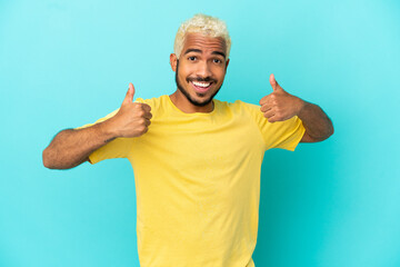 Young Colombian handsome man isolated on blue background giving a thumbs up gesture