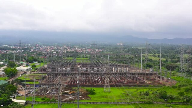 Distributing high voltage power substation in regional town viewed from above on a block of land made of insulators, poles, wires and transformers. High voltage energy transformer station, aerial view