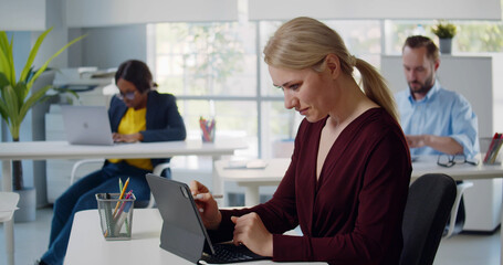 Young woman designer using graphic tablet sitting at workplace in creative office.