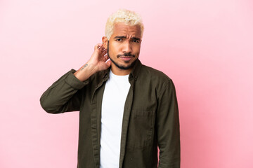 Young Colombian handsome man isolated on pink background having doubts