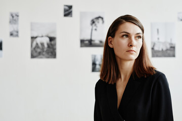Graphic portrait of elegant young woman wearing black in modern art gallery, copy space