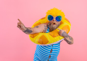 Fat amazed man with wig in head is ready to swim with a donut lifesaver