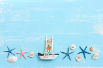 nautical concept with white decorative sail boat, seashells over blue wooden background
