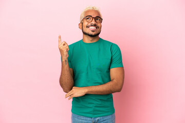 Young Colombian handsome man isolated on pink background pointing up a great idea