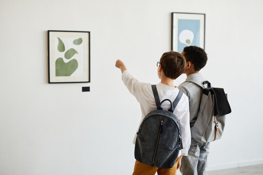Minimal back view of two schoolboys looking at paintings in modern art gallery, copy space