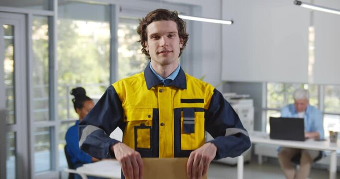 Young male courier delivering post to modern office