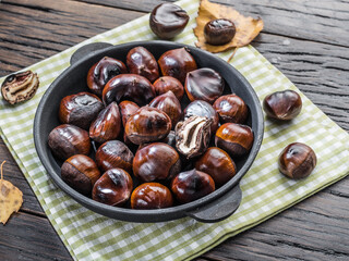 Roasted edible chestnut fruits in the pan. Top view.