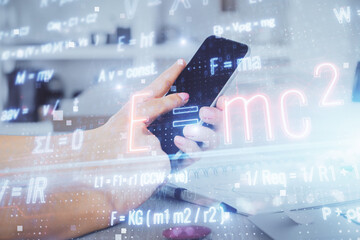 Double exposure of man's hands holding and using a phone and formulas drawing. Education concept.