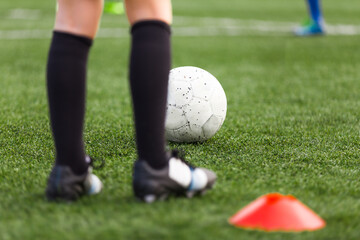 Obraz premium Soccer Player Footballer Sportsman on Training Field. Young Soccer Player on Practice Pitch. Red Soccer Cone. Players Kicking White Sports Ball on Grass Venue