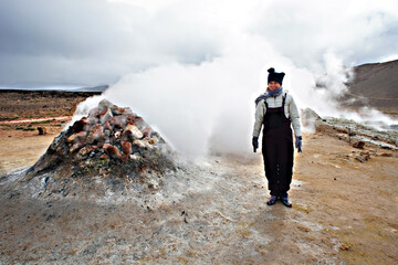 Young woman in overalls traveling in Hverir geothermal area in North of Iceland, Boiling volcano...