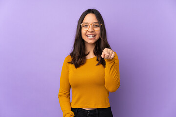 Young mixed race woman isolated on purple background surprised and pointing front