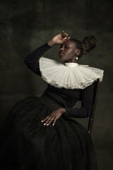 Portrait of medieval African young woman in black vintage dress with big white collar posing...