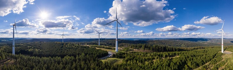 modern wind turbines in front of a blue and cloudy sky panorama