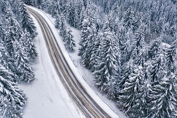 Snowy mountain road and forest, drone view.