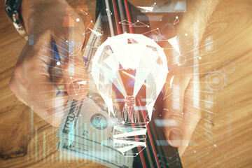 Multi exposure of bulb drawing hologram and USA dollars bills and man hands. Business Idea concept.