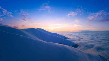 Fototapeta na wymiar Dawn or sunset over the snow-capped mountains. View from the drone.