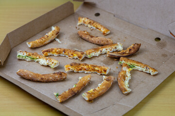 Pizza crusts in a cardboard box. Leftover pizza close-up. Unhealthy food
