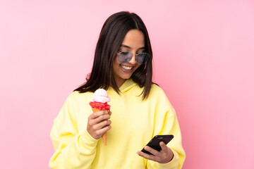Young brunette girl holding a cornet ice cream over isolated pink background holding coffee to take...