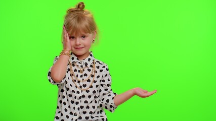 Funny playful blonde kid child showing thumbs up and pointing empty place, advertising area for commercial text, copy space for goods promotion on chroma key background. Cute teenager children girl