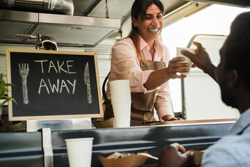 Hispanic woman serving take away food inside food truck - Focus on waiter face
