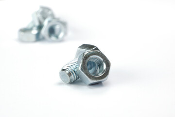 Nut and bolt isolated on white background with group of bolts and nuts in the background out of focus. Close up image