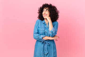 pretty arab woman smiling happily and daydreaming or doubting