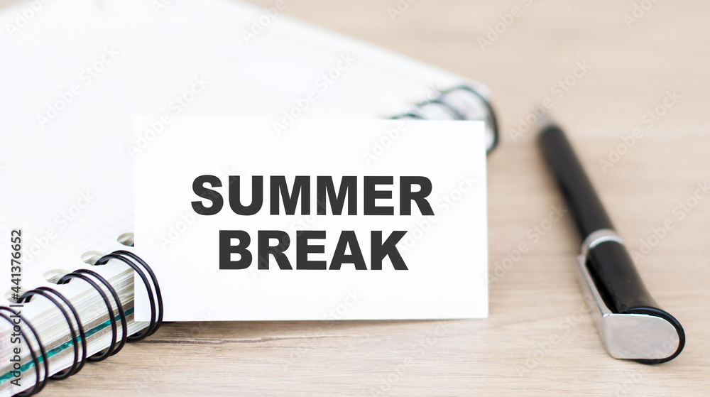 Poster text summer break on a white card on the table next to a notepad and pen. local tourism, lockdown va