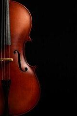 CLOSE UP OF HALF A CELLO ON BLACK BACKGROUND. CLASSICAL MUSIC INSTRUMENTS CONCEPT.