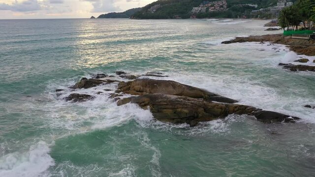.Aerial top view of white waves in green sea hit on the large rocks in summer day. .Beach sea space area. green sea, waves crashing on the rocks.. At Kalim Beach Phuket Thailand.