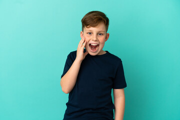 Little redhead boy isolated on blue background with surprise and shocked facial expression