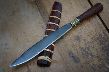 knife custom or Enep in the natural wood scabbard on old table background handmade of Thailand - obrazy, fototapety, plakaty