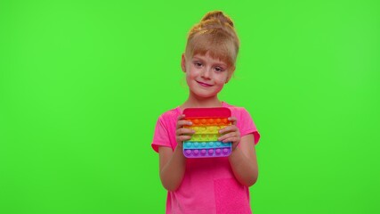 Child kid play with pop it sensory toy on chroma key background. Girl presses on colorful squishy silicone touch screen bubbles. Stress anxiety relief. Trendy fidgeting game of stressed children