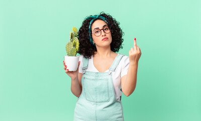 pretty arab woman feeling angry, annoyed, rebellious and aggressive and holding a potted cactus