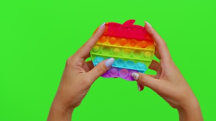 Fototapeta na wymiar Hands playing with pop it sensory anti-stress toy isolated on chroma key. Girl presses on colorful rainbow bubbles squish. Stress anxiety relief. Trendy fidgeting game for stressed children and adults