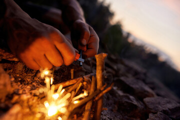 Close up of male hands making a fire with flint and steel in the wild
