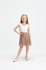 Beautiful little girl in modern stylish dress posing isolated on white studio background. Happy childhood concept.
