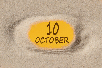 October 10. 10th day of the month, calendar date. Hole in sand. Yellow background is visible through hole. Autumn month, day of the year concept